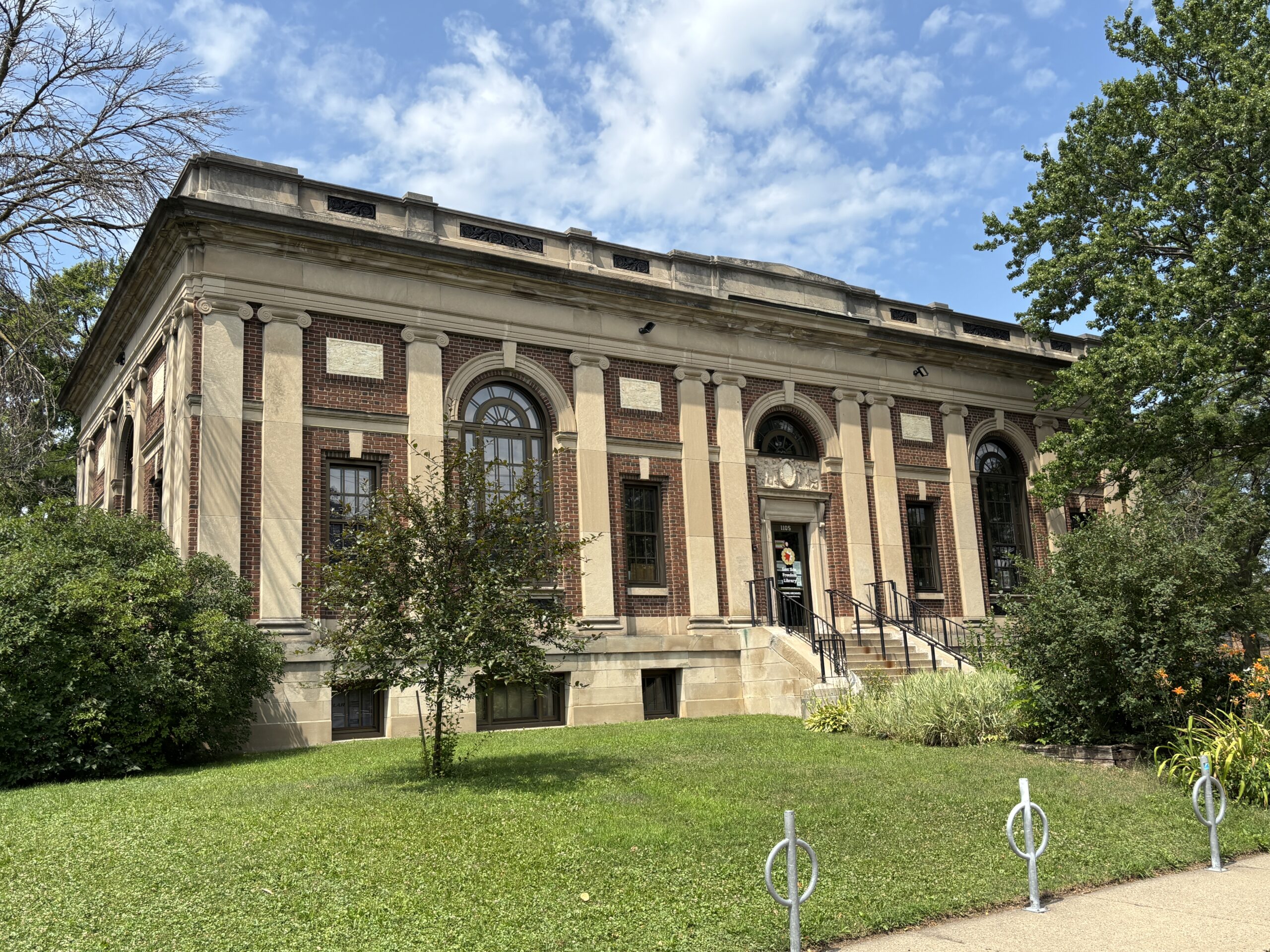 Photo of the front of the East Side Freedom Library building. Grass lawn and stairs leading up to a brick building with columns.